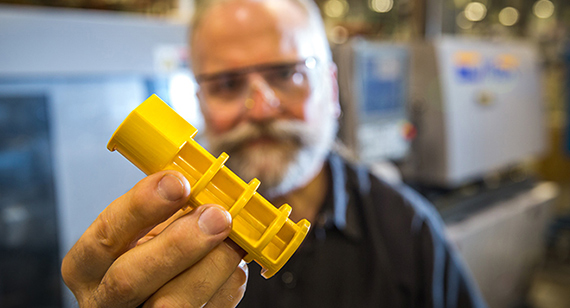technician holding yellow injection molded part from protolabs