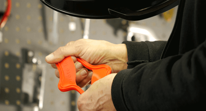 Hands holding an orange rubber part